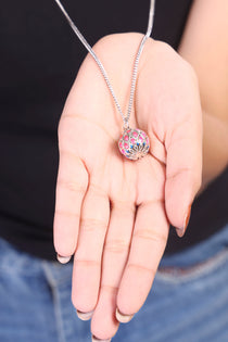 A 925 silver harmony ball bola necklace resting on a baby bump, showcasing the soothing chime pendant for mothers.