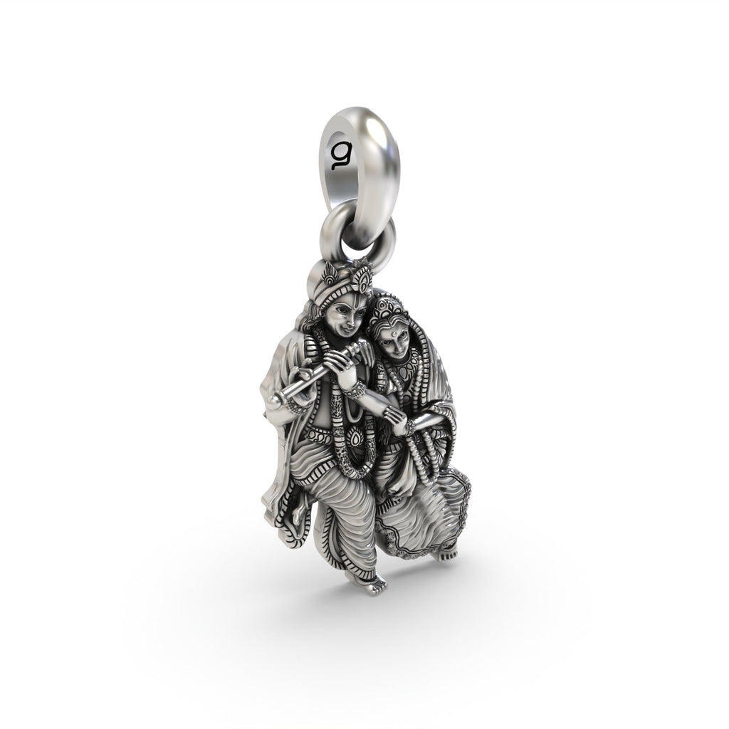The silver Radha Krishna pendant held in hand to show its scale and hollow back design for lightweight comfort.