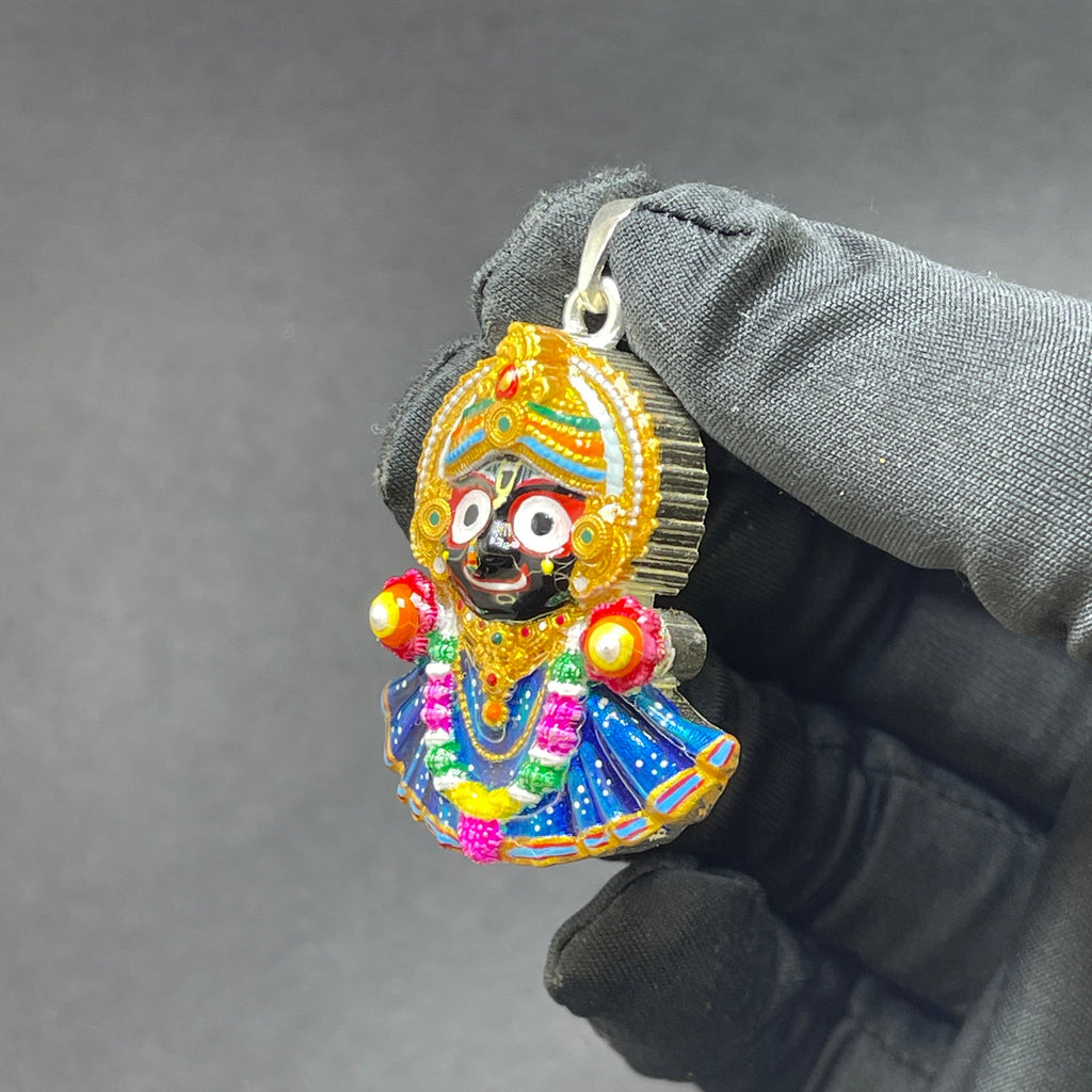 Hand-held view of the 925 silver Jagannath pendant to show its size and the fine Meenakari details.