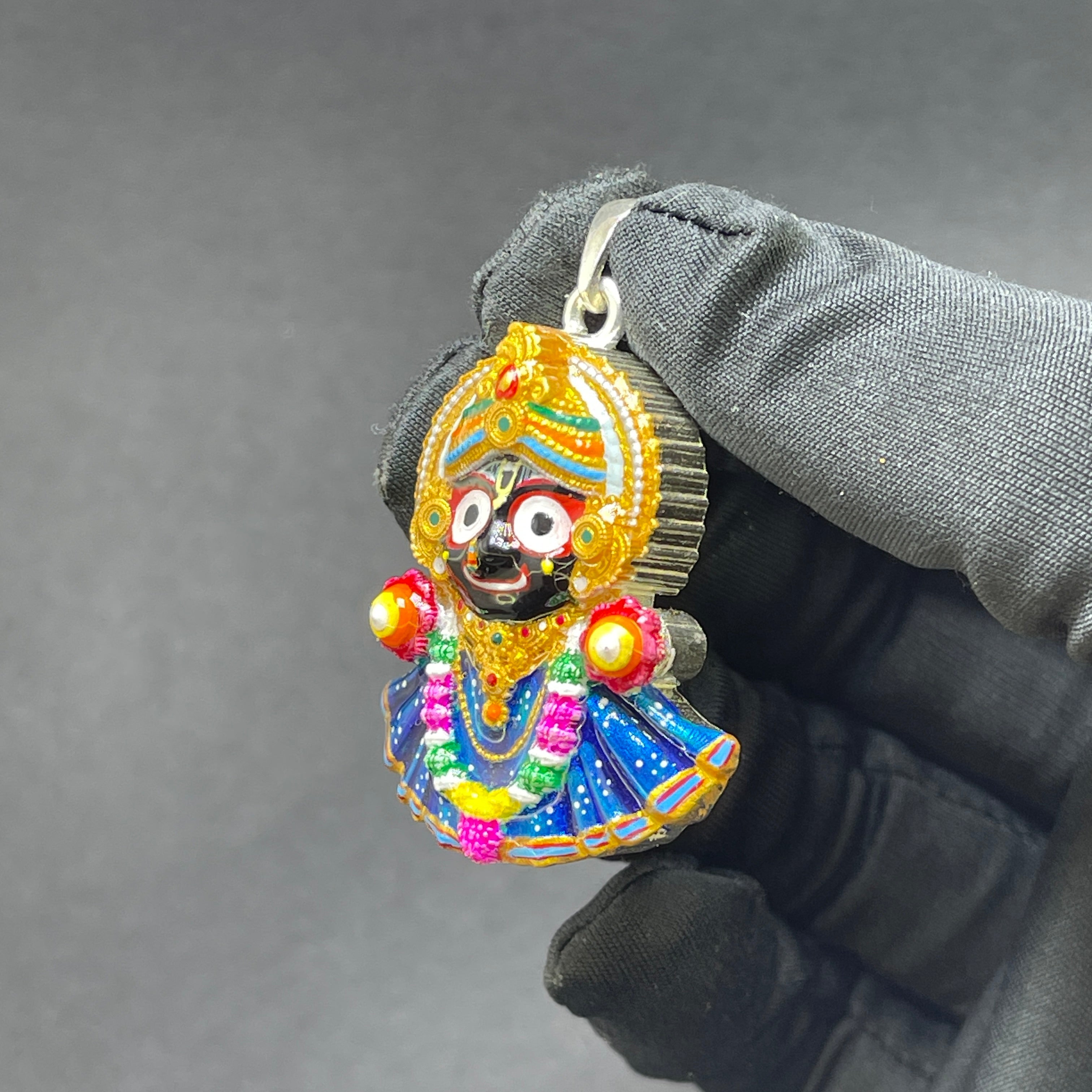 Hand-held view of the 925 silver Jagannath pendant to show its size and the fine Meenakari details.