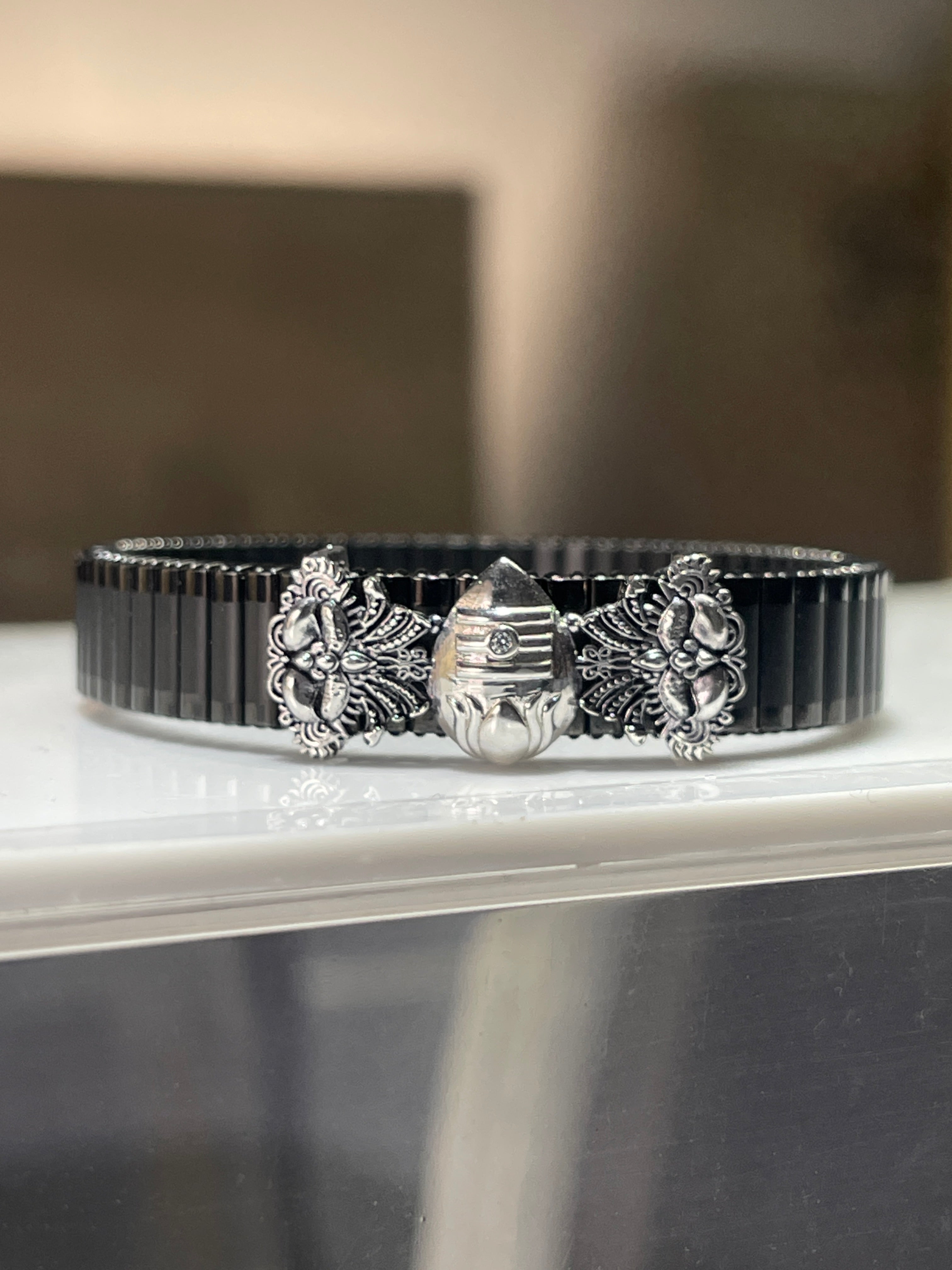 Front view of the Alankar Murugan Vel bracelet for men, showcasing the intricate silver-plated Vel design on the black band.