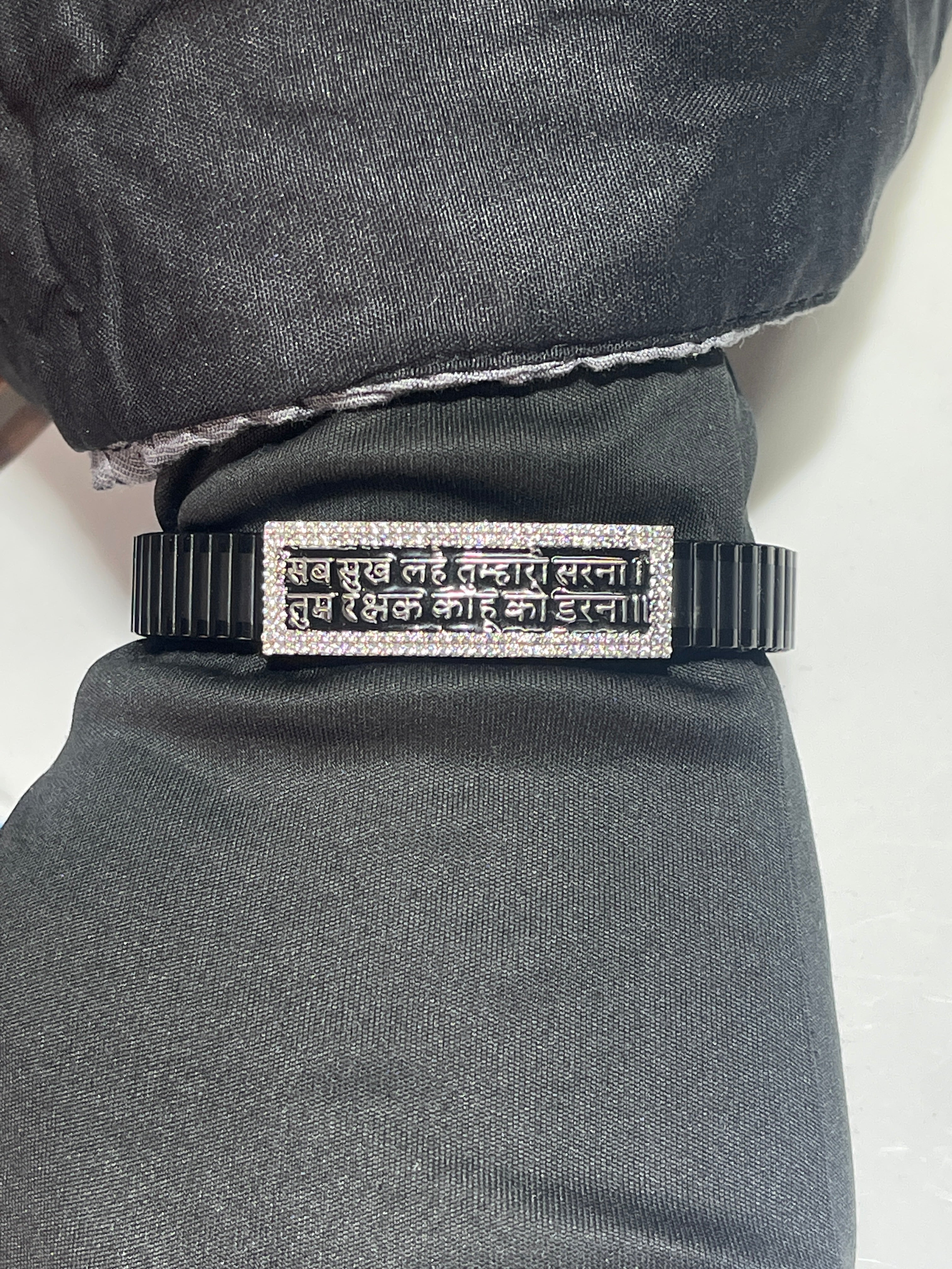 The complete Hanuman Chalisa bracelet showing the flexible black stainless steel strap and silver mantra plate.