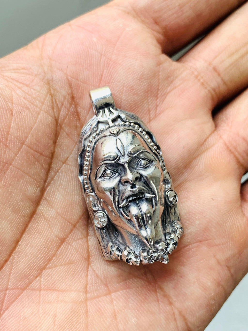 A person wearing the 925 sterling silver Kali Maa face pendant to show its size and how it hangs on a chain.